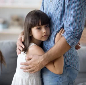 A young girl hugs her father.