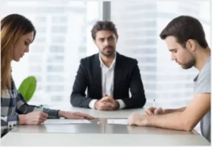 A couple signing documents in the presence of a lawyer.