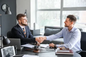 Lawyer and client shaking hands in a professional office setting.