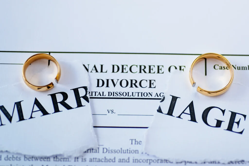 Paperwork that says marriage that is ripped with two golden rings.