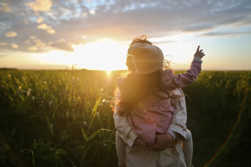 A parent holding their child when the sun is setting.