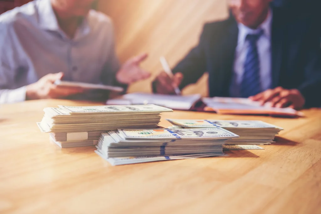 Two attorneys speaking with a stack of money in front of them.