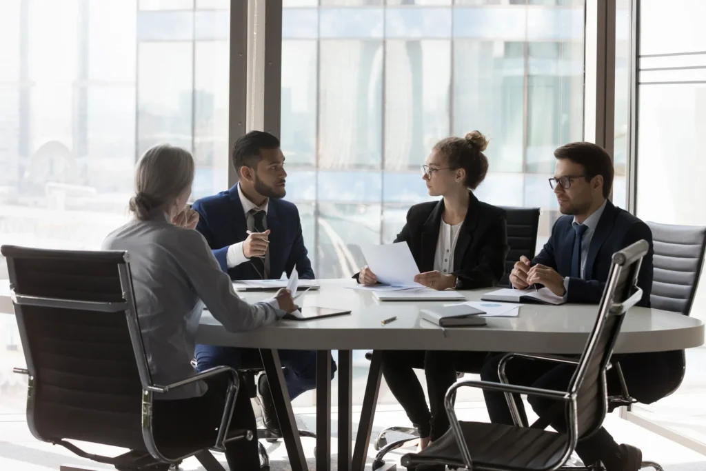 Two attorneys and their clients gathered around a table during divorce mediation.